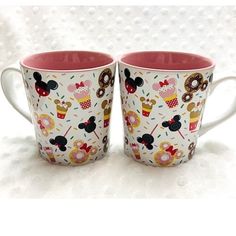 two coffee mugs with mickey and minnie mouse designs on them are sitting side by side