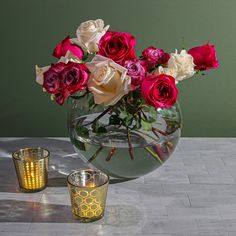 a vase filled with lots of different colored flowers next to two candles on a table