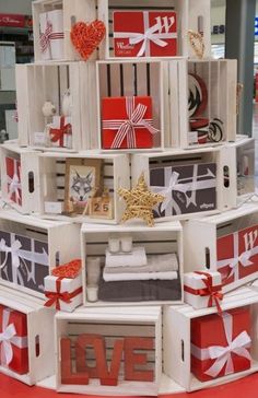 a christmas tree made out of crates and wrapped in red, white and grey paper