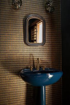 a blue sink sitting under a bathroom mirror next to a wall mounted faucet