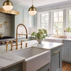 a kitchen with marble counter tops and gold faucets on the windowsills