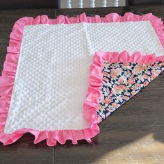 two pink and white placemats sitting on top of a wooden floor next to each other