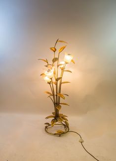 a lamp that is on top of a white surface with flowers in the light bulb