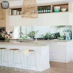 a kitchen with white counter tops and wooden stools next to an island in the middle