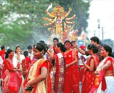 a group of women in red and yellow saris standing next to each other on the street