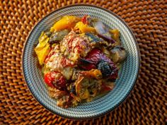 a white bowl filled with food on top of a wooden table next to a wicker place mat