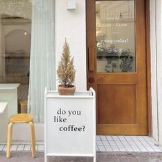 a sign that says do you like coffee? in front of a door with a potted plant on it