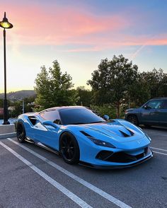 a blue sports car parked in a parking lot next to a street light and some cars