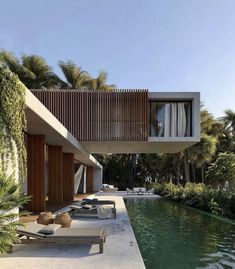 an outdoor swimming pool next to a house with wooden slatted walls and windows