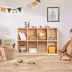 a teddy bear sitting on the floor in front of a book shelf filled with toys