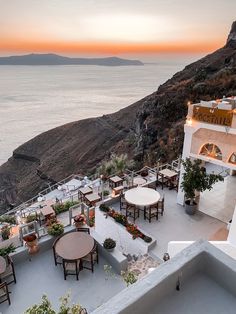 an outdoor dining area overlooking the ocean at sunset