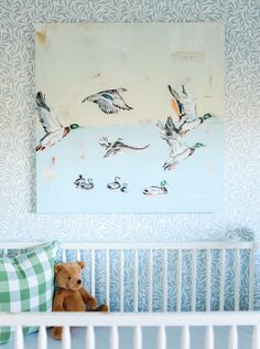 a teddy bear sitting in a crib next to a wall with ducks on it