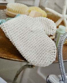 a bath mitt sitting on top of a wooden table next to a hair dryer