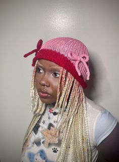 a woman with blonde dreadlocks and a pink hat on her head is looking at the camera