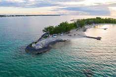 an island in the middle of the ocean with trees on one side and houses on the other