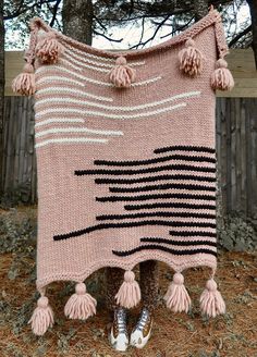 a pink blanket with tassels hanging from it's sides in front of a tree