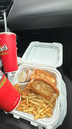 there is a sandwich, french fries and soda in the back seat of a car