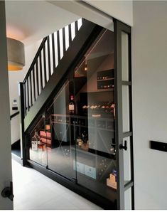 an open door leading to a wine cellar in a house with stairs and glass walls