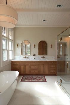 a large bathroom with two sinks and a bathtub next to a window in the corner