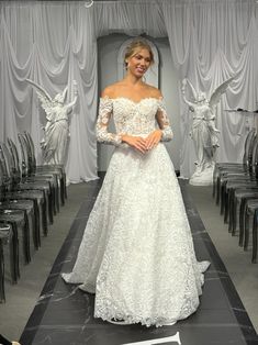 a woman in a white wedding dress standing on a runway