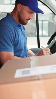 a man sitting in the driver's seat of a truck writing on a piece of paper