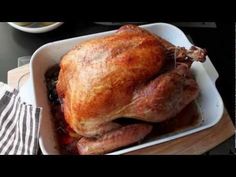 a large turkey sitting in a white dish next to bowls of apples and pears