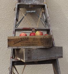 an old wooden ladder with apples in it hanging on the side of a building next to a wall