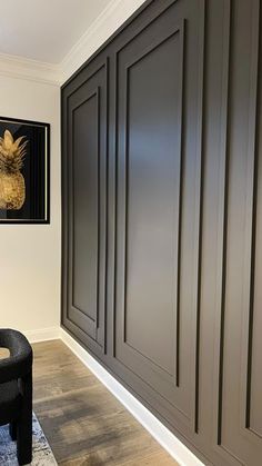 a black chair sitting in front of a wall with wooden paneling on it's sides