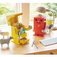 a desk with a keyboard, mouse and toy figures sitting on it next to a window