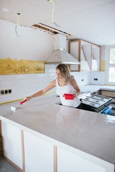 a woman in a white top is cleaning the kitchen counter with a red spatula