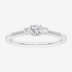 a white gold engagement ring with three stones on the band and a round brilliant diamond center