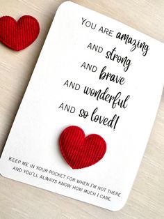 two red hearts sitting on top of a card with the words you are amazing and strong and brave and wonderful and so loved