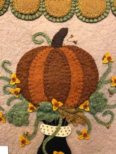 a close up of a piece of art with a pumpkin and flowers on the side