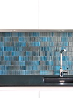 a kitchen sink under a faucet in front of a blue tile backsplash