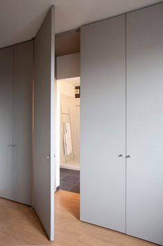 an empty room with white closet doors and wood flooring