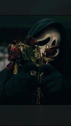 a person wearing a mask with roses in front of them and a black cloth covering the face