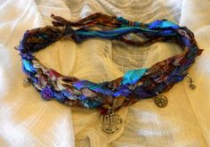 This beautiful hand made choker is created by me using 7 strands of recycled Fair Trade Sari Silk.  Multiple colors and versatility are perfect for using as a choker or bracelet.Fair Trade Recycled Sari Silk, Gem stones, Antique bronze charms, beads more Description Our Gorgeous Bohemian Recycled Sari Silk Ribbon Wrist Wrap. .beautifully hand dyed in browns, blues, and different shades of purple! Our Silk Ribbon comes from Fair Trade India and is made using strips of recycled saris each sewn tog Sari Silk Jewelry, Silk Wrap Bracelets, Silk Jewelry, Recycled Sari Silk, Wrist Wrap, Silk Wrap, Sari Silk, Love Charms, Fair Trade