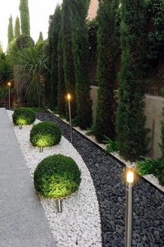 an outdoor garden with gravel and lights in the center, surrounded by greenery on either side