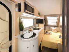 the interior of a camper with a sink and microwave on it's side