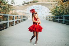 a girl in a red dress holding an umbrella