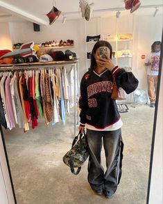 a person taking a selfie in front of a closet full of shirts and hats