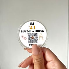 a person holding up a button that says i'm 21 buy me a drink