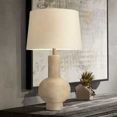 a table lamp sitting on top of a wooden table next to a vase with a succulent plant