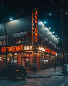 a neon sign on the side of a building that says junior's restaurant bar