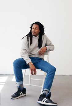 a man with dreadlocks sitting in a white chair and looking off to the side