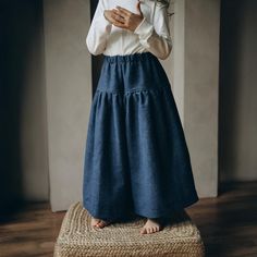 a woman standing on top of a wooden floor wearing a white shirt and blue skirt