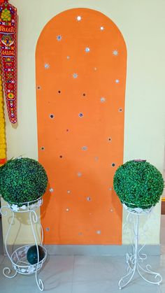 two potted plants in front of an orange wall