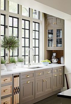 a kitchen filled with lots of counter top space next to large windows and potted plants