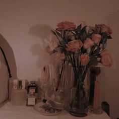 a vase filled with lots of pink flowers on top of a white table next to other items