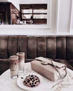 two cookies and milkshakes on a marble table in front of a brown couch